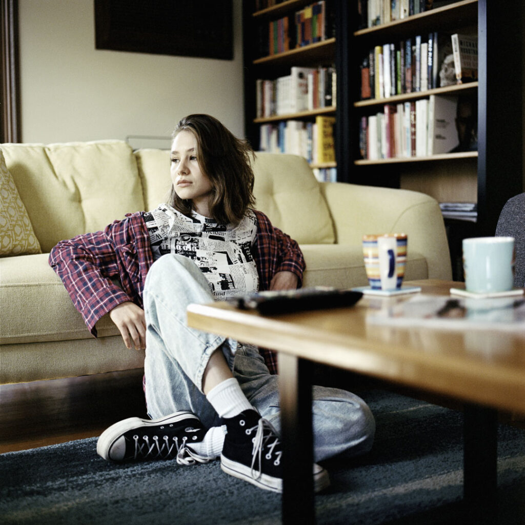 Portrait of young woman with her morning coffee and a book case full of books made with Kodak Portra 400 medium format film